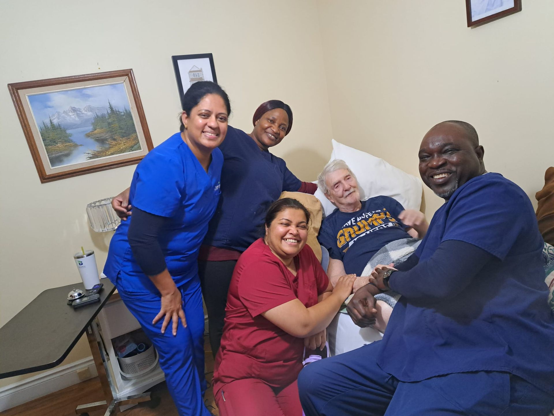 Five people smiling and posing together in a room, with one seated in a blue chair