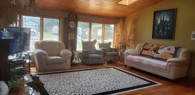 Cozy sunroom with leather chairs, a sofa, and a patterned rug under warm wood ceilings.