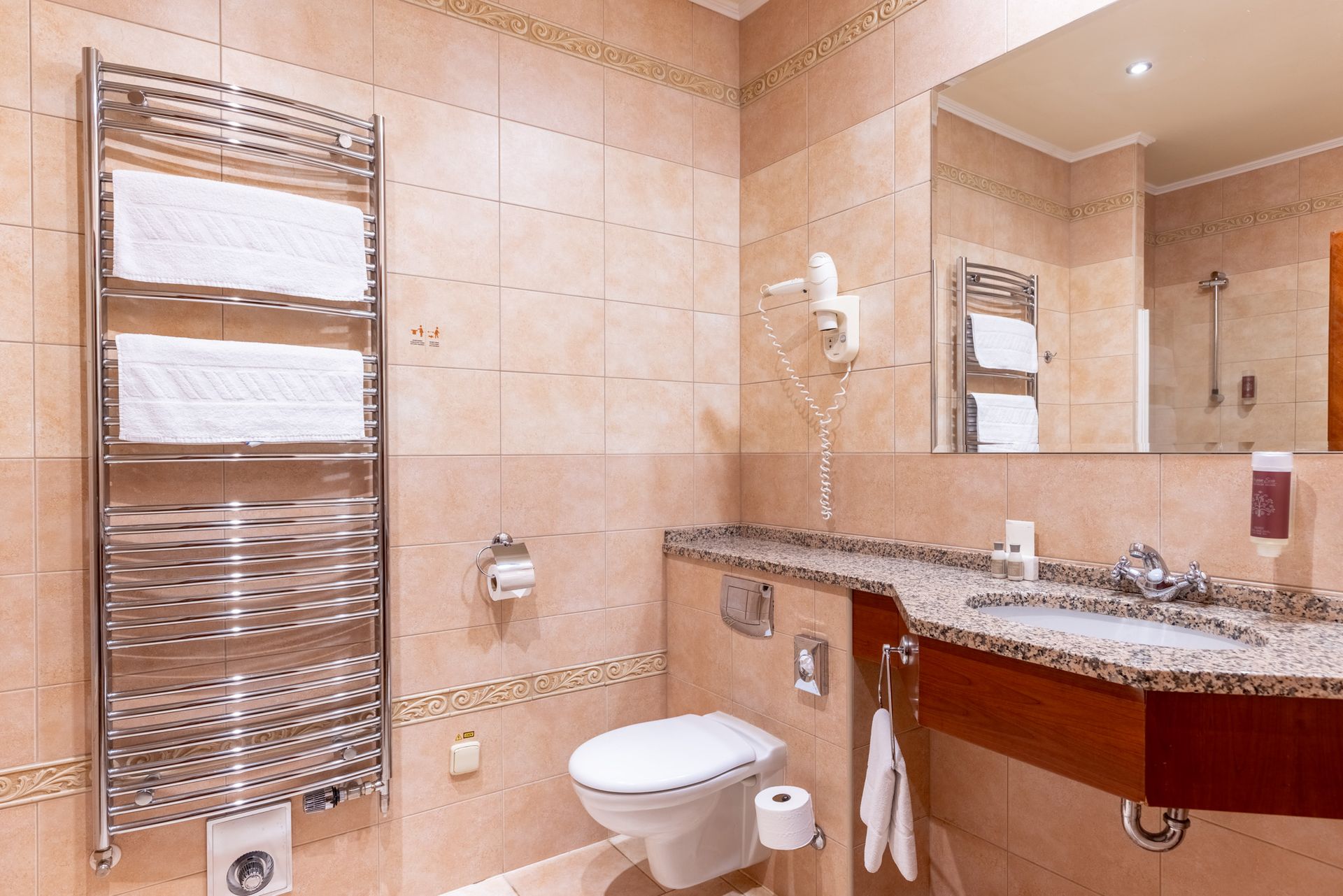Koupelna s WC, umyvadlem, zrcadlem a věšákem na ručníky.