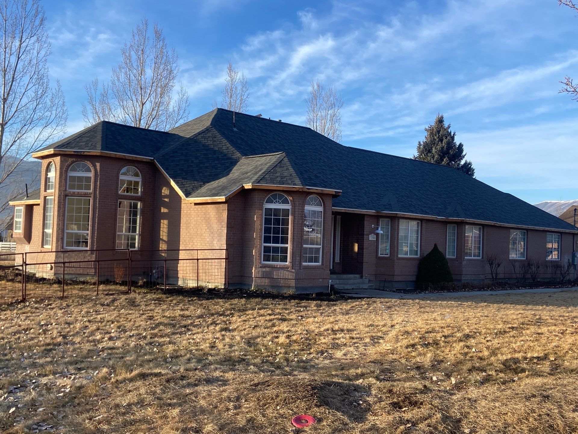 Single-story brick building with dark roof in a dry field under a blue sky