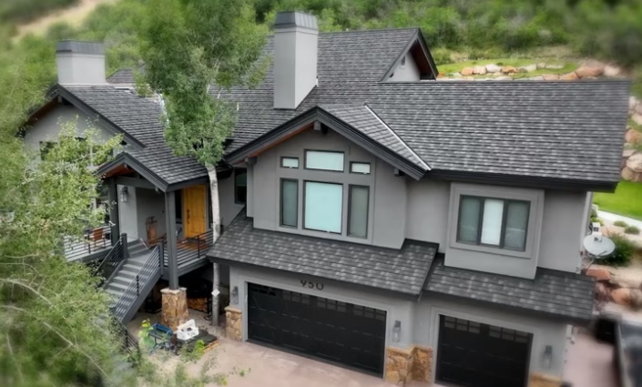 Worker installing black roof underlayment on a steep roof