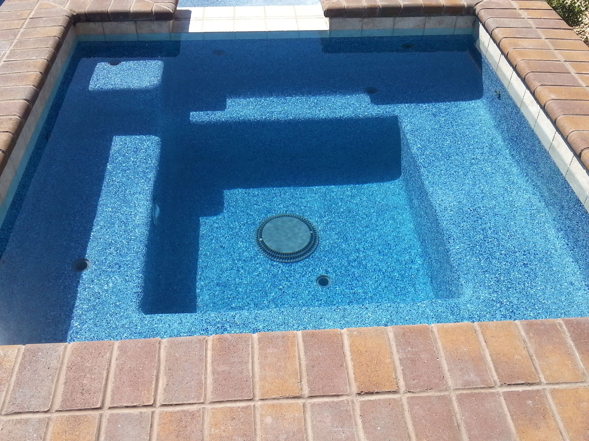 A swimming pool with a brick border and blue water