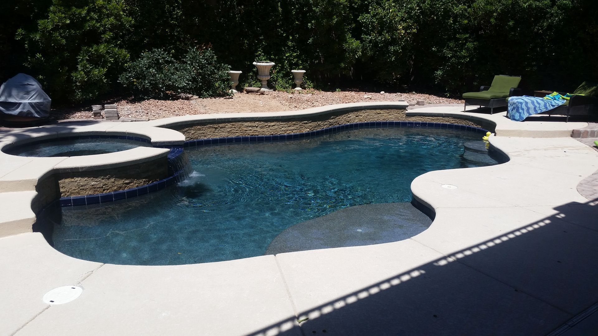 A large swimming pool surrounded by lawn chairs and trees