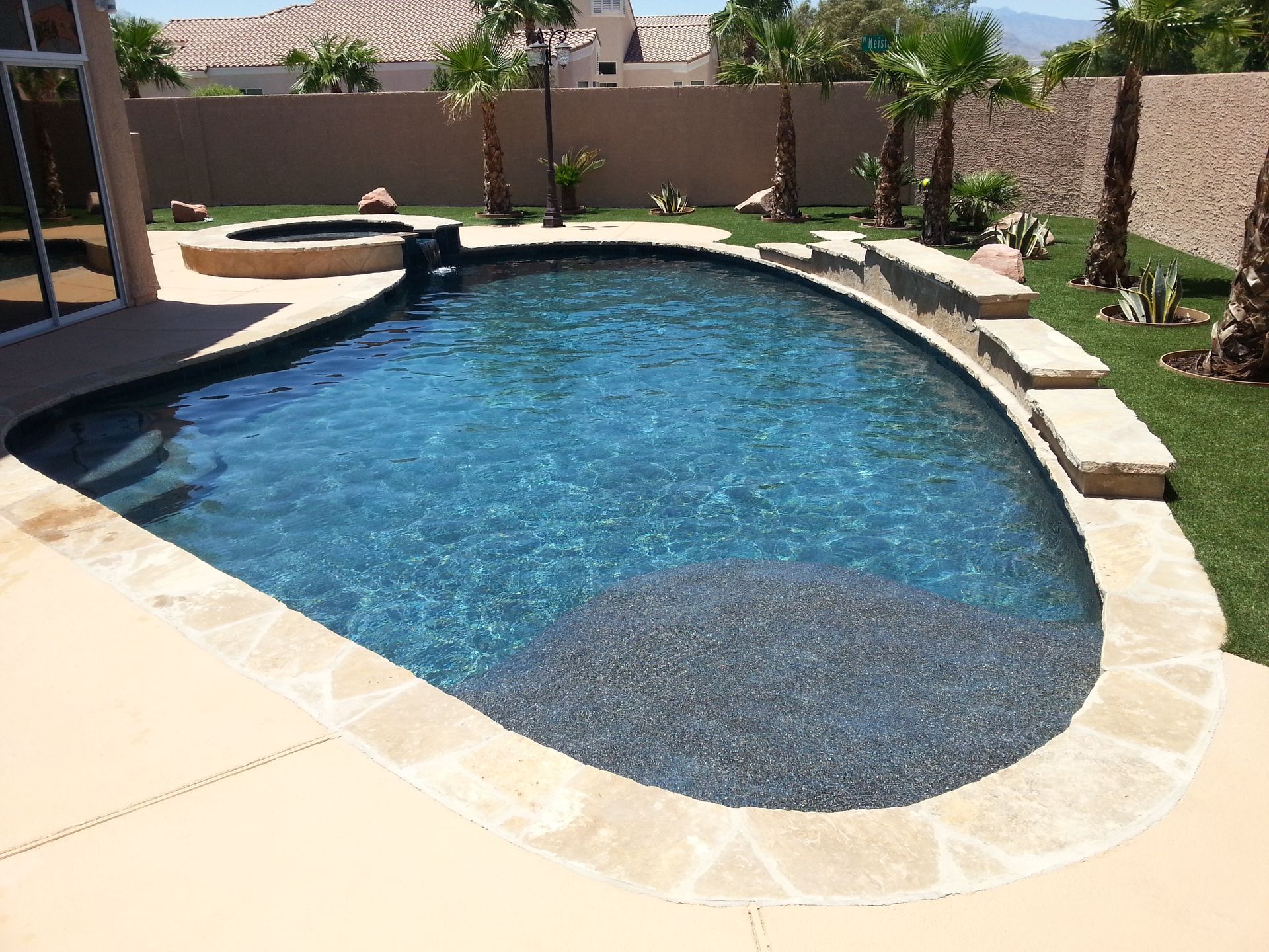 A large swimming pool surrounded by palm trees in a backyard
