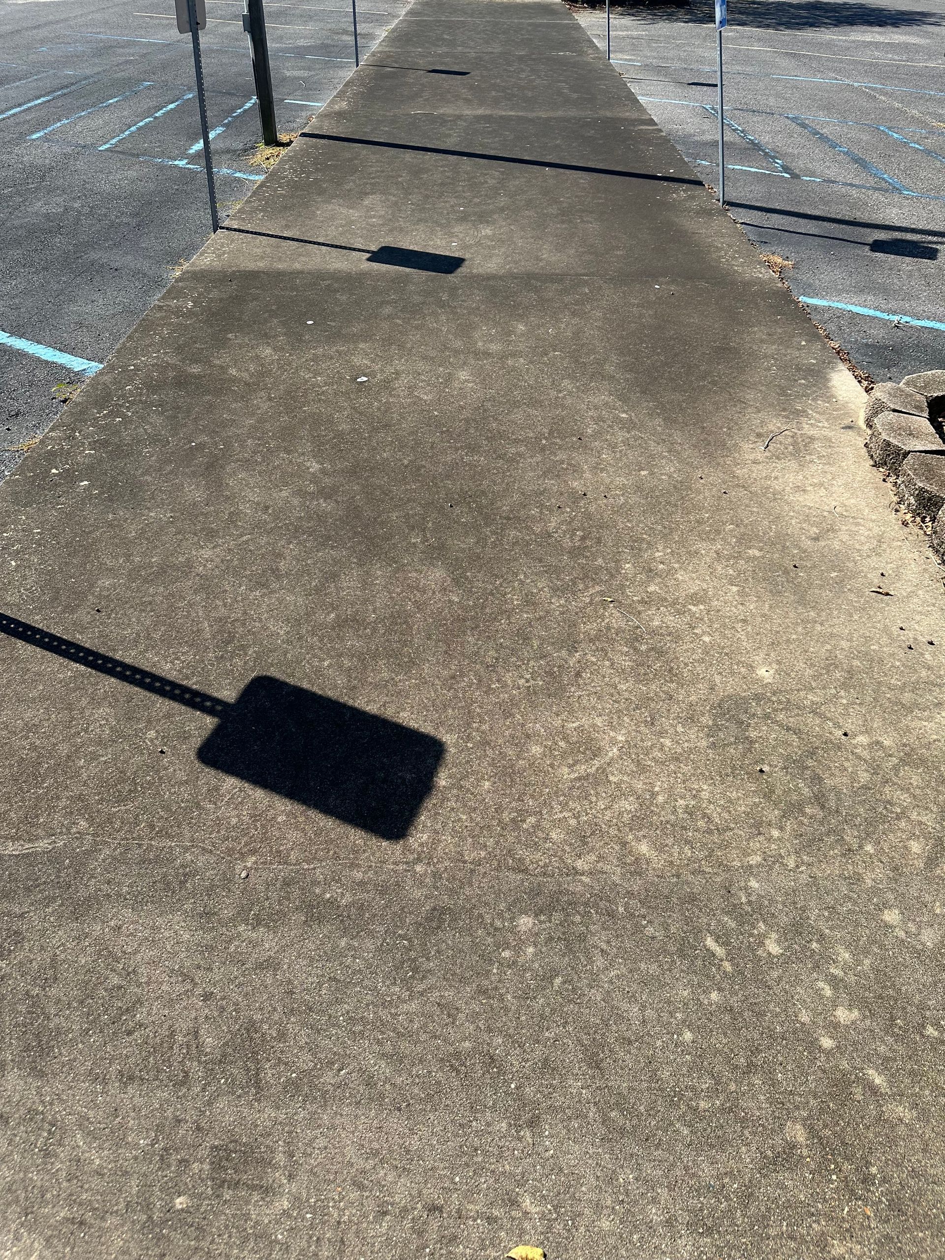 Concrete sidewalk with shadows in outdoor parking lot.