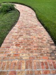 Brick pathway winding through green grass.