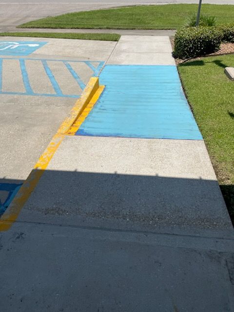 Accessible ramp painted blue and yellow, connecting a sidewalk to a parking area.