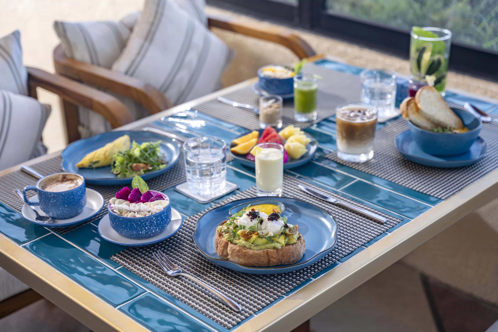 Breakfast table set with various dishes and drinks, blue and white tones.