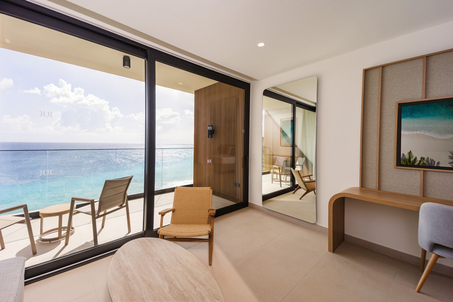 Hotel room interior with beige sofa, wooden accents, and a large mirror.