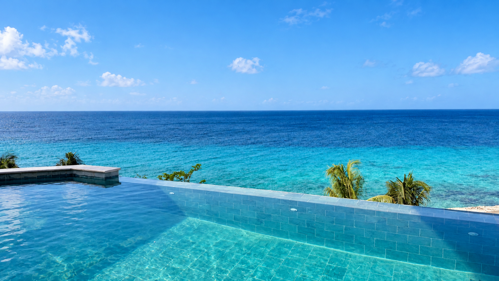 Poolside lounge chairs beside a turquoise pool, with a person relaxing in the water.
