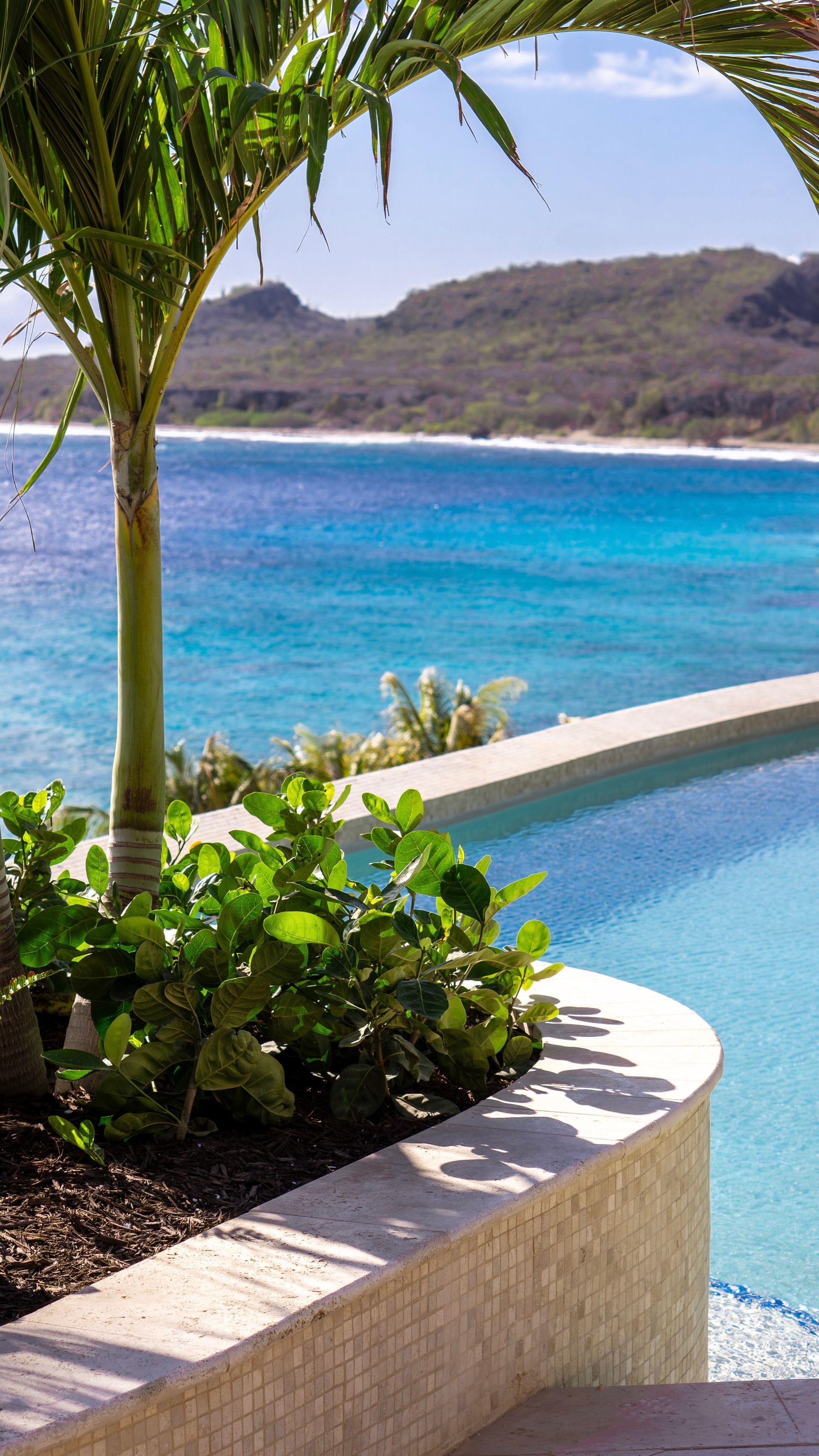 Zwembad- en strandresort met palmbomen, ligstoelen en helder turquoise water.