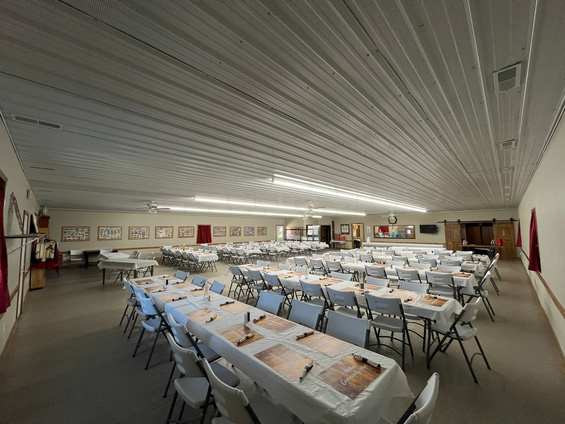 Large banquet hall with rows of long tables and chairs set for a meal or event