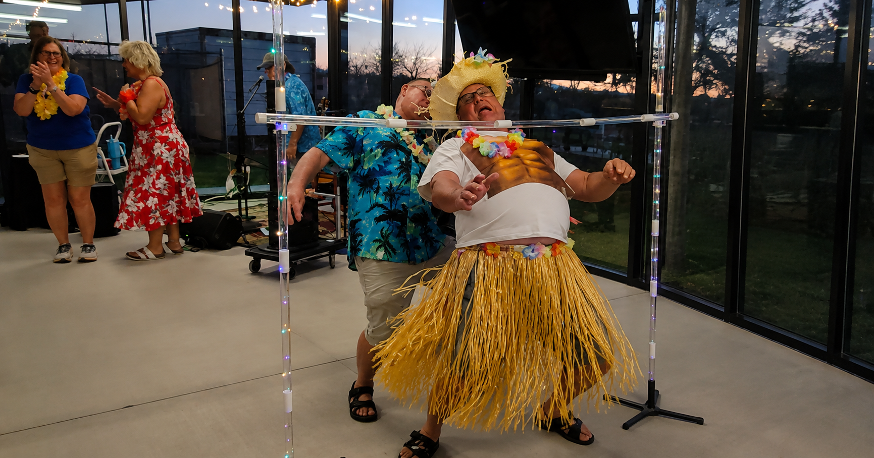 Four performers in colorful costumes dancing indoors in front of glass windows