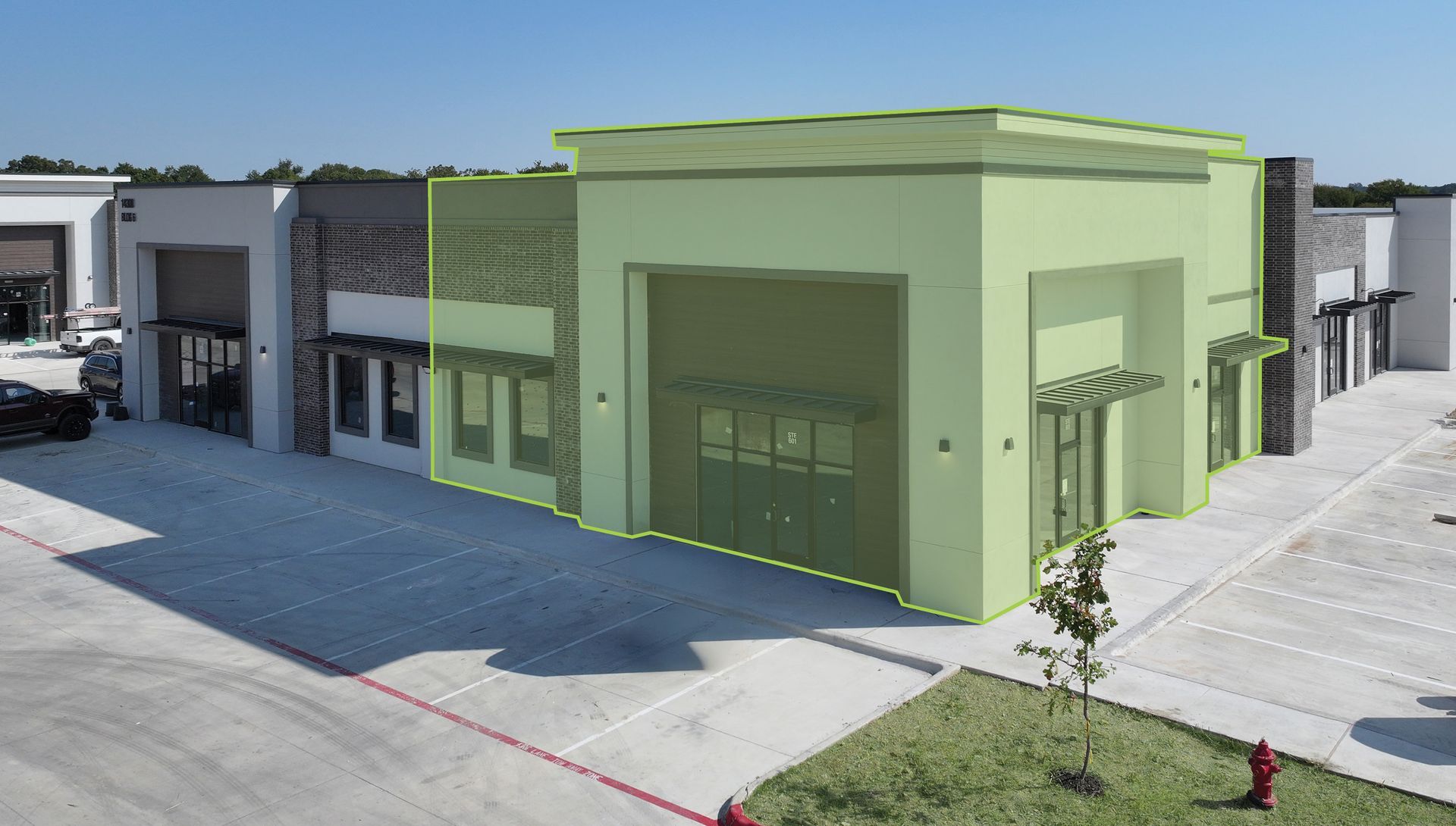 Green highlighted industrial building with garage door, awning, and adjacent structures.