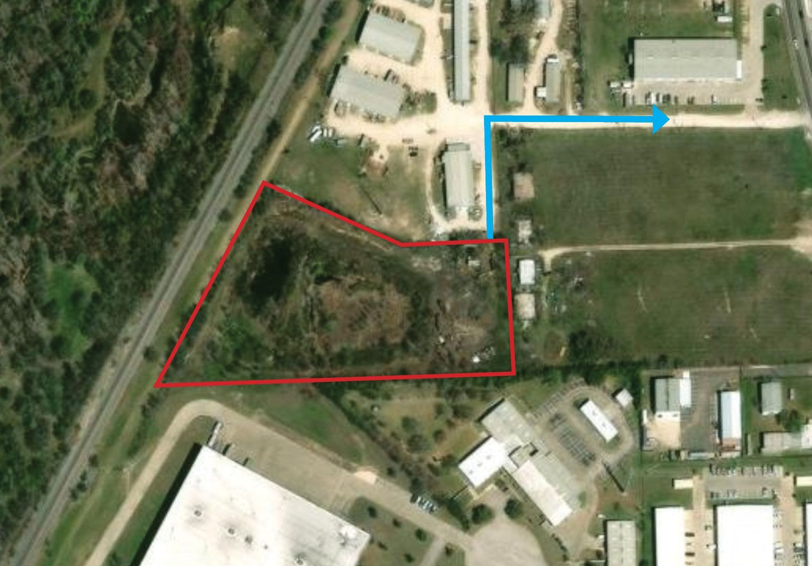 Aerial view of a lot outlined in red and blue beside roads, trees, and nearby buildings