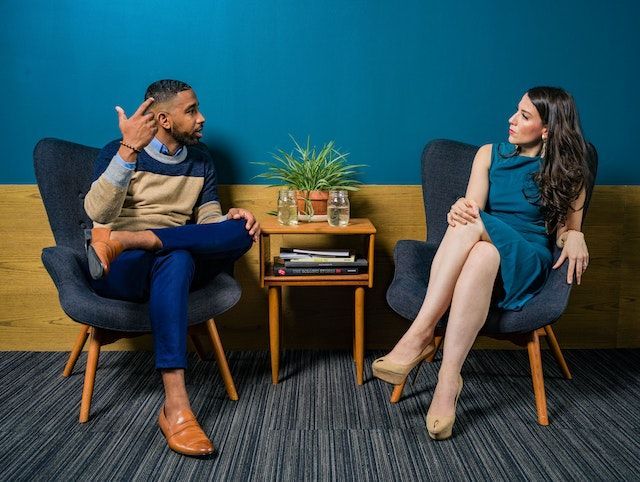 a man and a woman are sitting in chairs talking to each other .