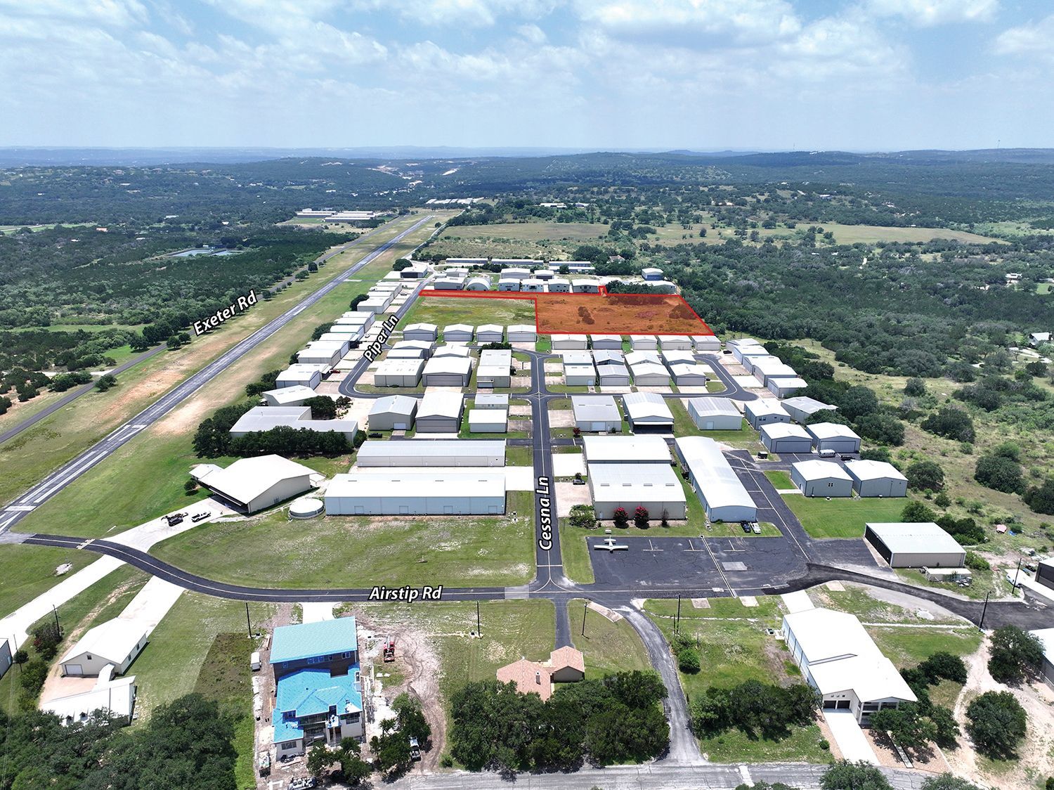 Aerial view of a sprawling industrial complex with white-roofed buildings, roads, and surrounding green landscape