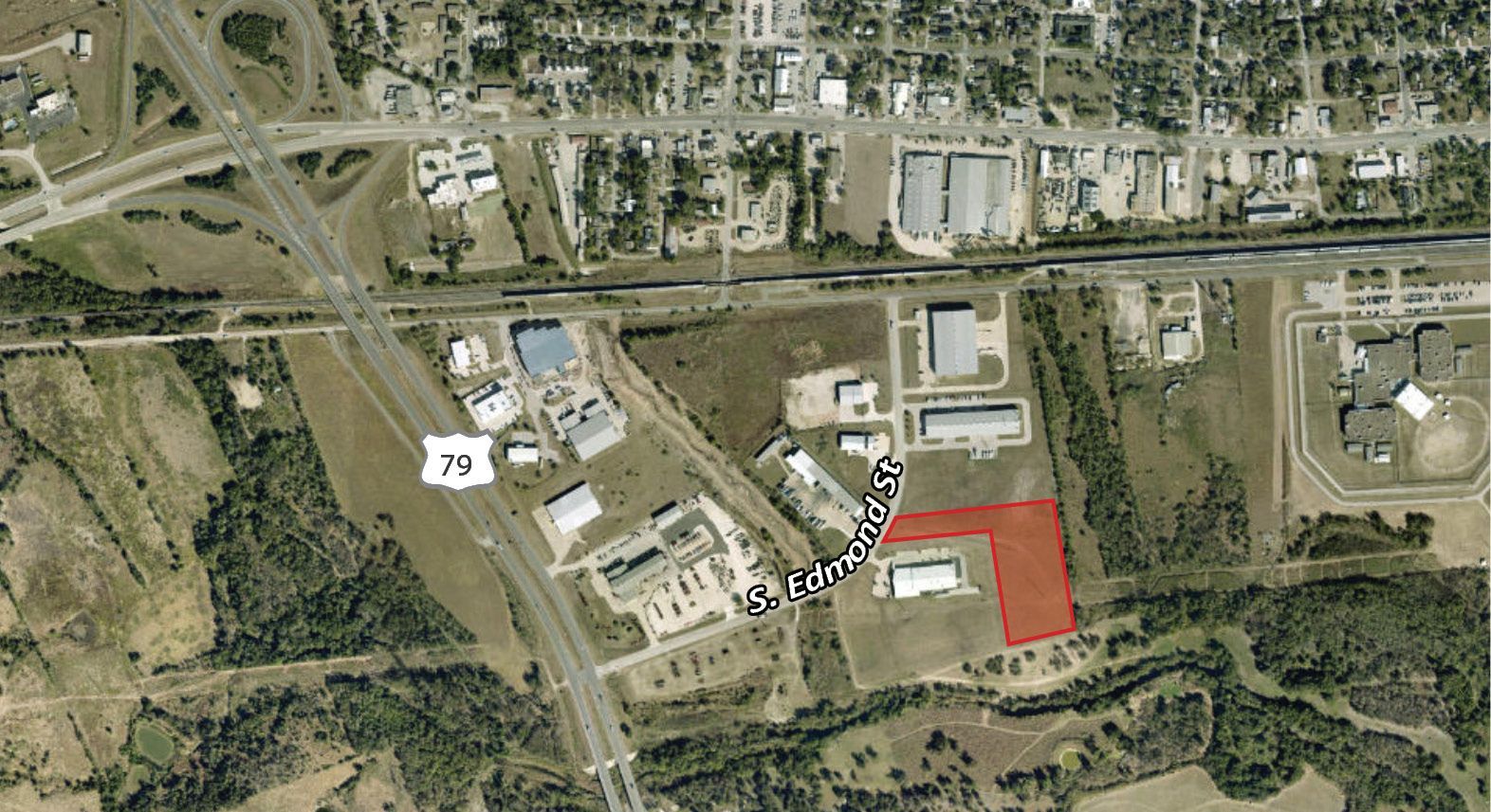 Aerial view of a campus with buildings, roads, trees, and a red highlighted area near the center.