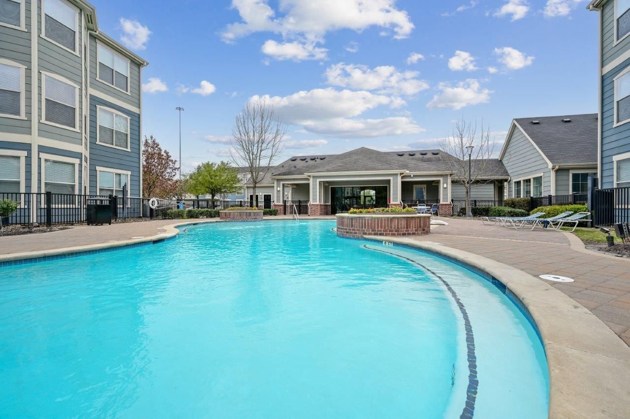 A large swimming pool surrounded by buildings in a residential area.