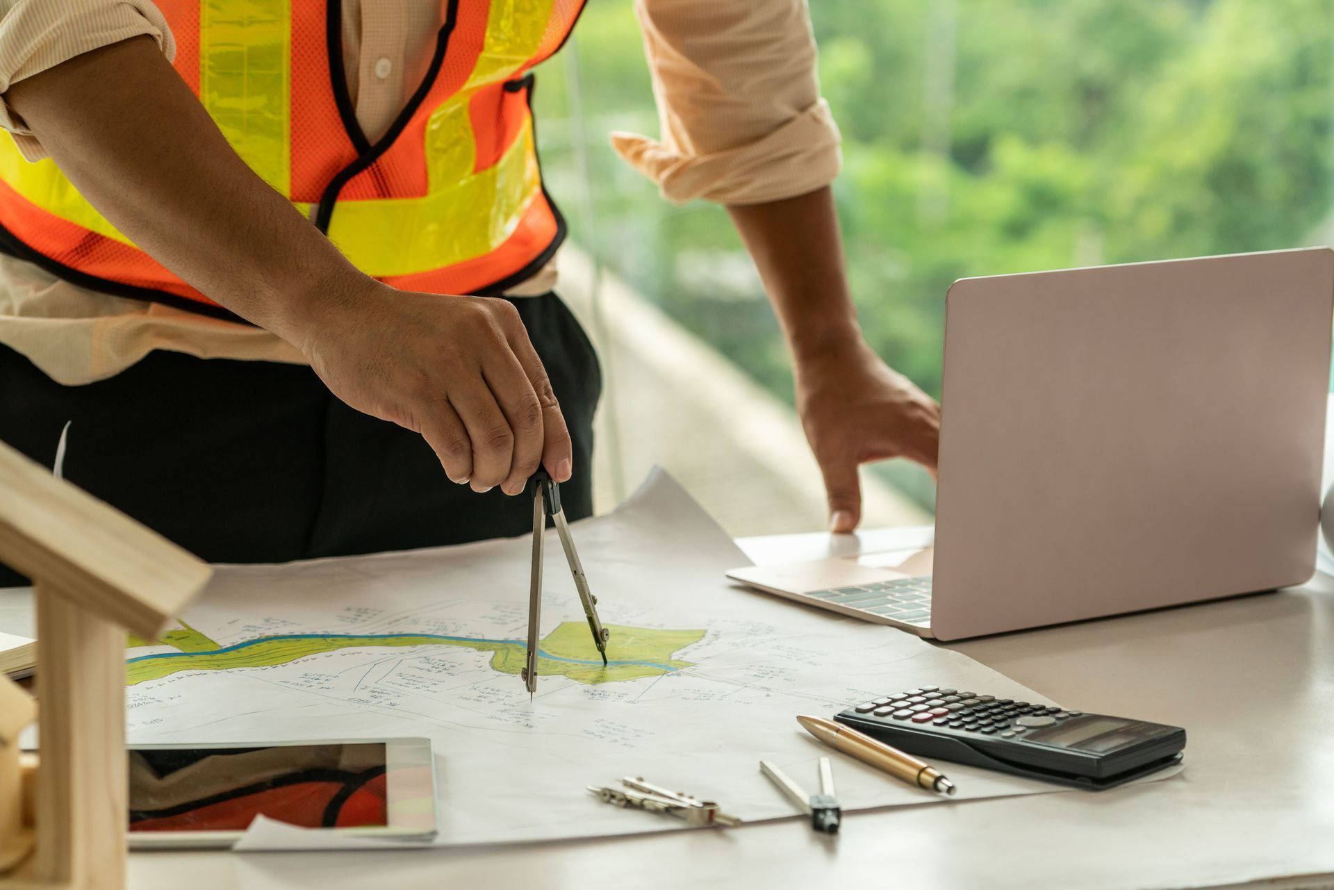 A construction worker is using a compass to draw a map on a blueprint.