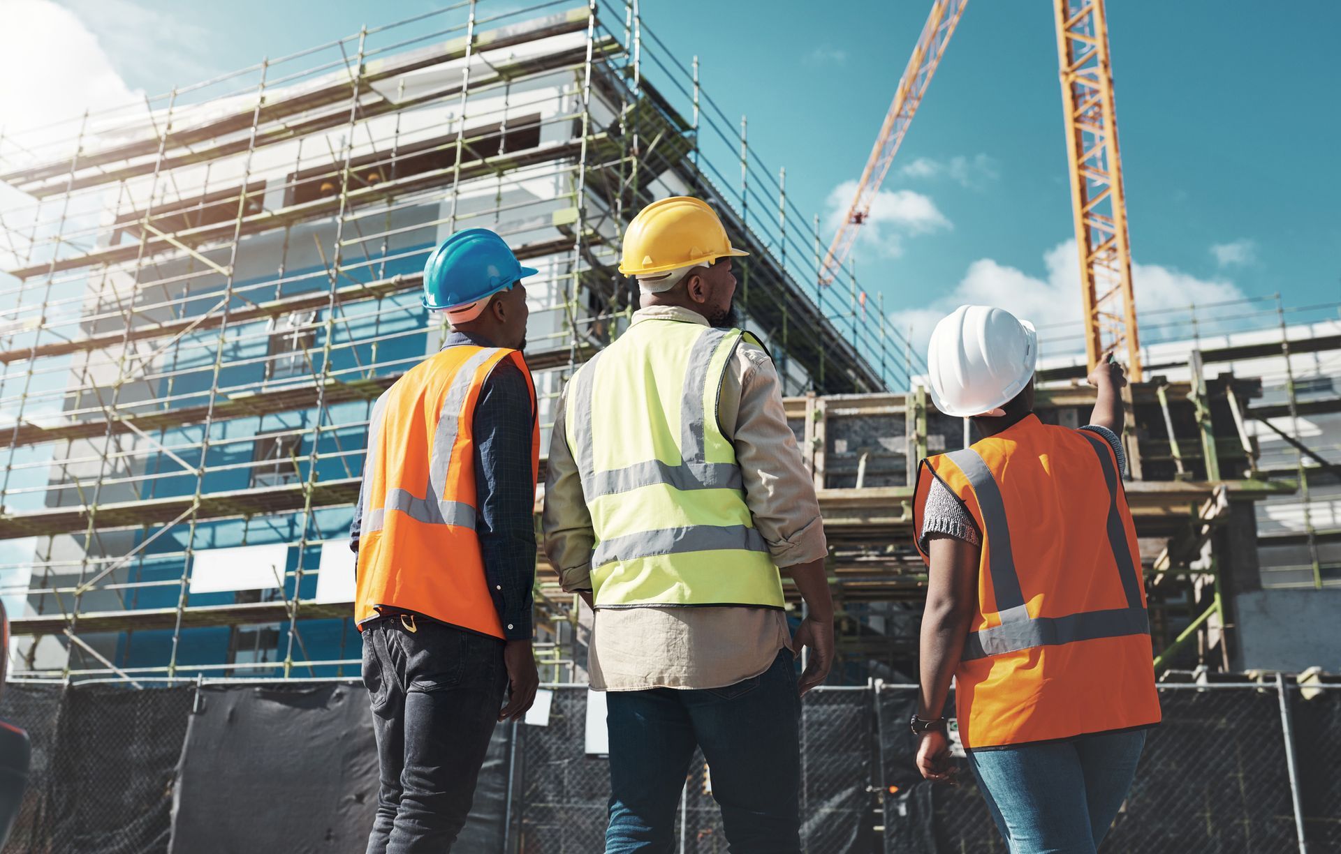 A group of construction workers are standing in front of a building under construction.
