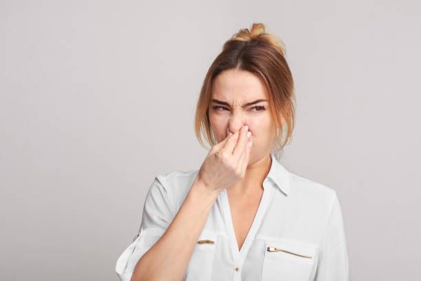 Une femme se couvre le nez avec sa main.