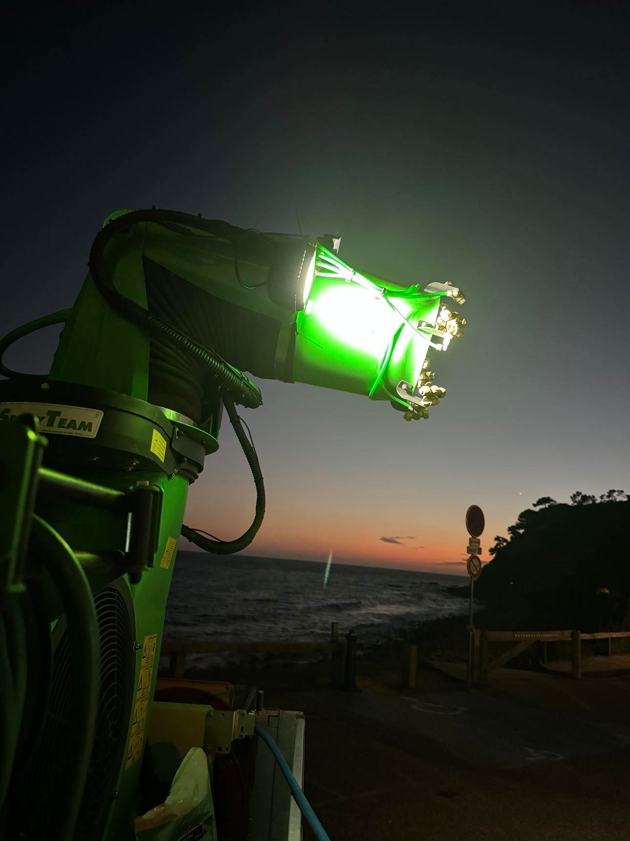 Une lumière verte brille sur une plage la nuit.