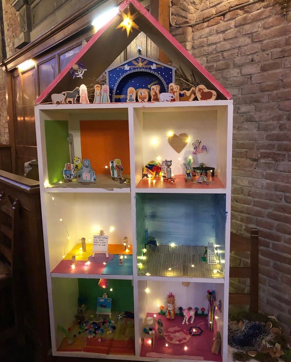 Houten huis met kamers ingericht door de kinderen en tieners als kerstproject: voor iedereen is er plek in het huis van God