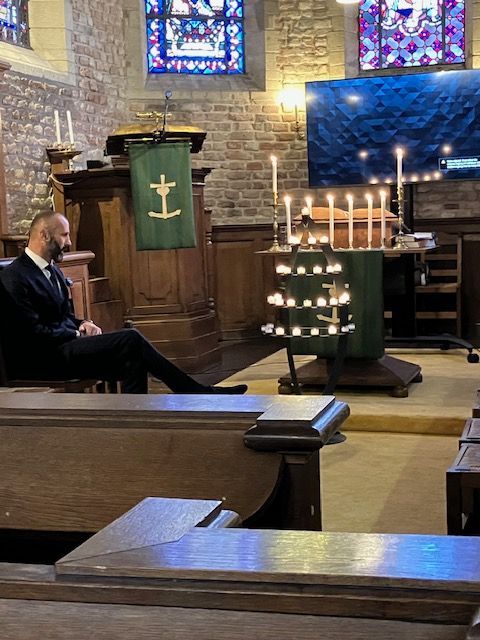 Eeuwigheidszondag met kaarsjes aansteken waarbij pastor Poesiat op de stoel zit