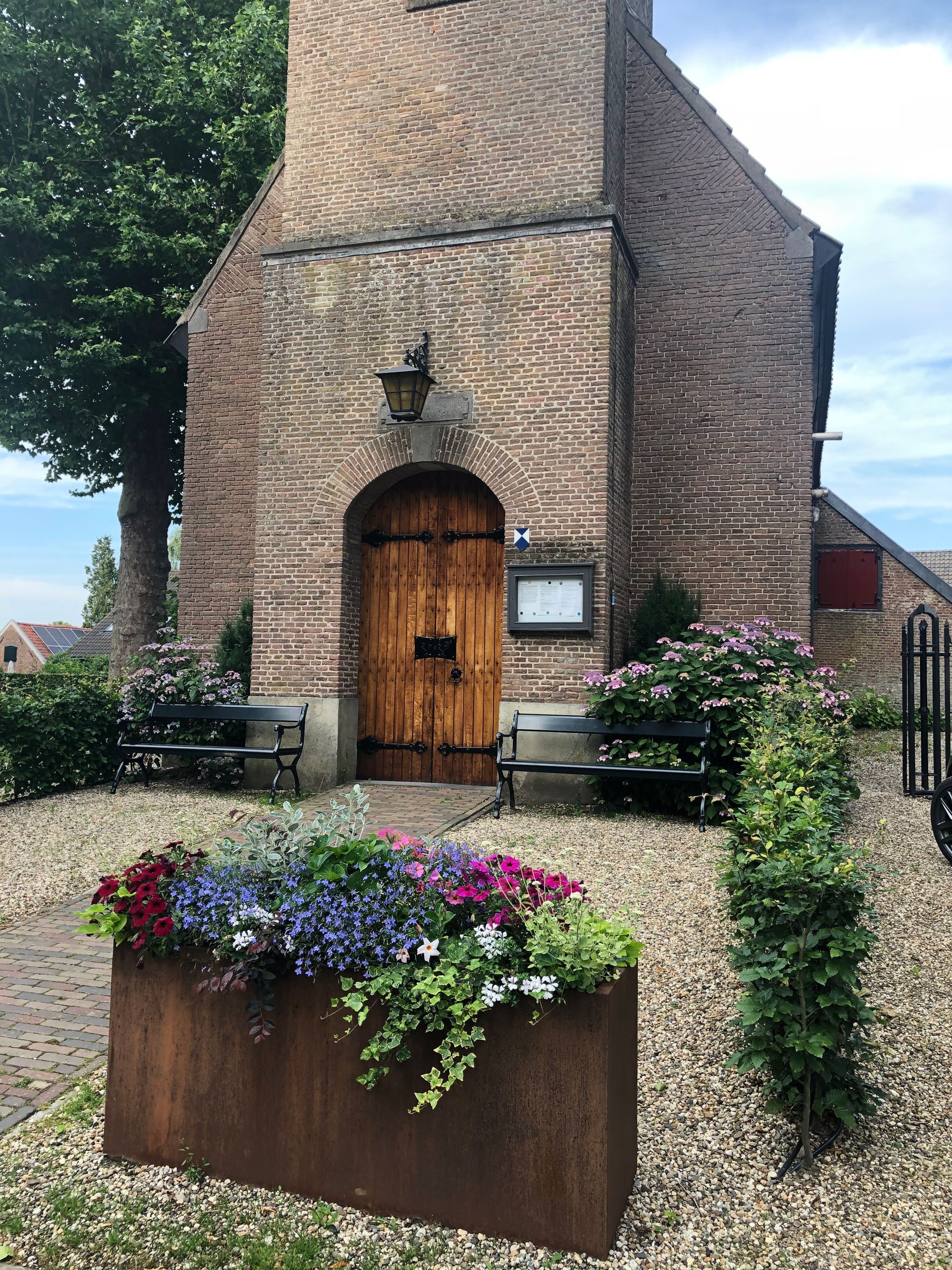 kerk ingang met bloembakken en banken bij de ingang
