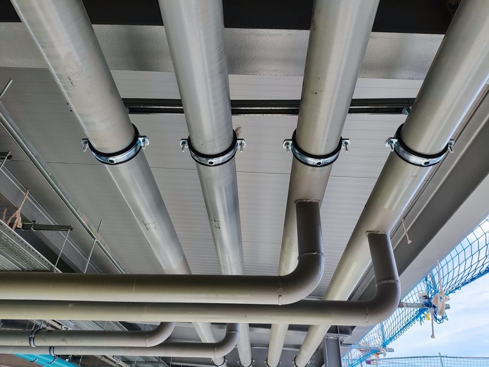Gray Pipes Secured to a Ceiling With Metal Clamps — Sunset Plumbing NT in Moil, NT