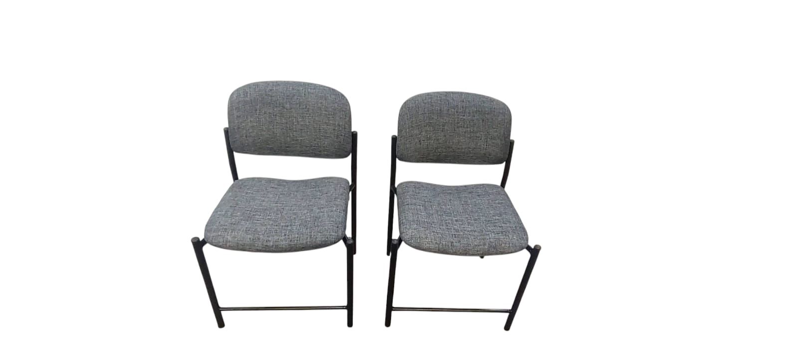 Dos sillas tapizadas en gris con patas de metal negro, una al lado de la otra sobre un fondo blanco.