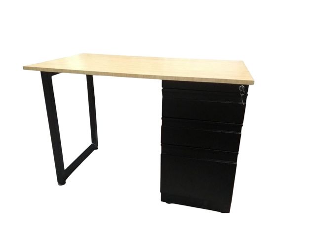 Escritorio sencillo con tablero de madera clara, patas de metal negro y un armario con cajones negro a la derecha.