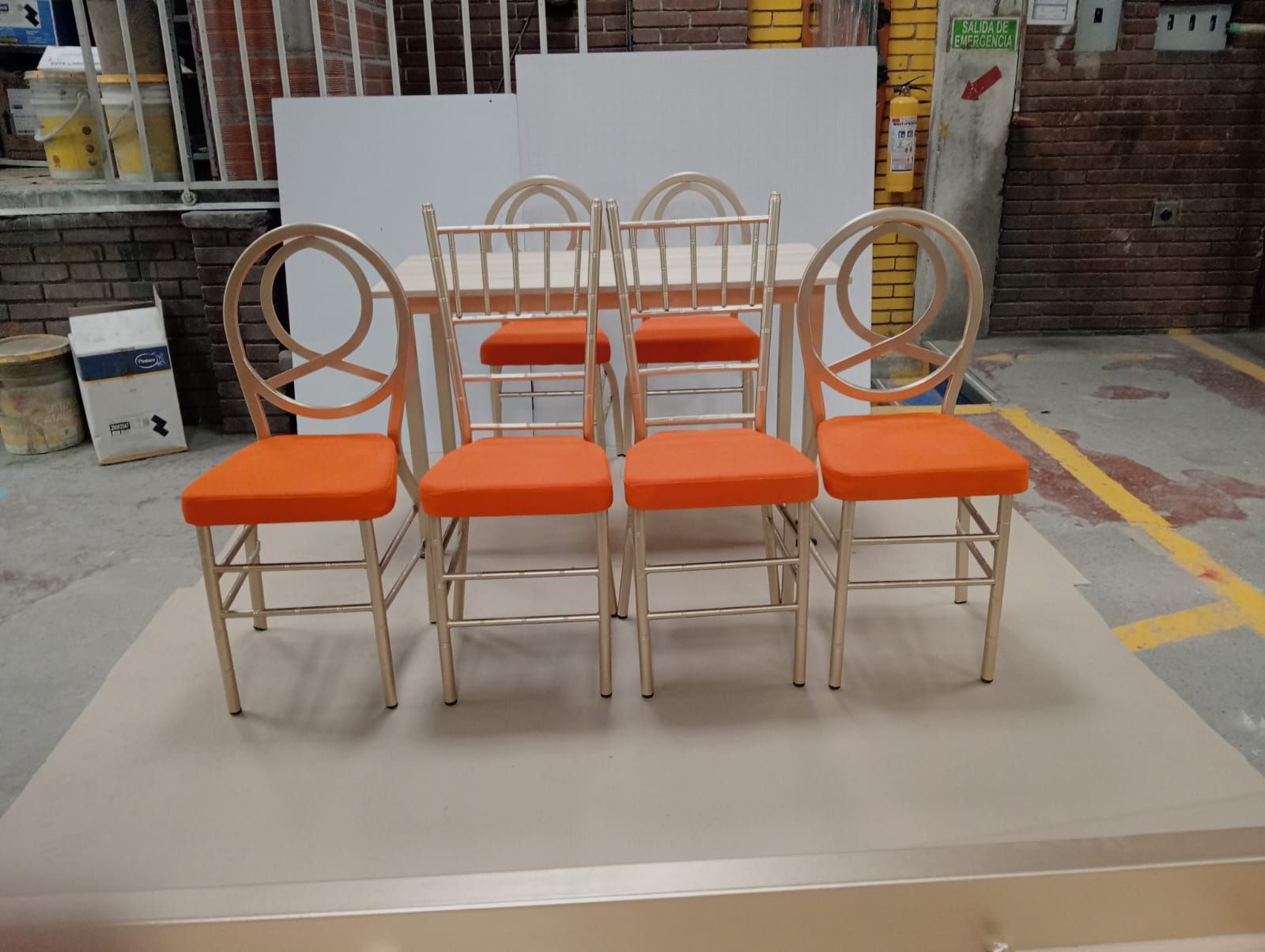 Seis sillas beige con cojines naranjas dispuestas sobre una plataforma en un escaparate.