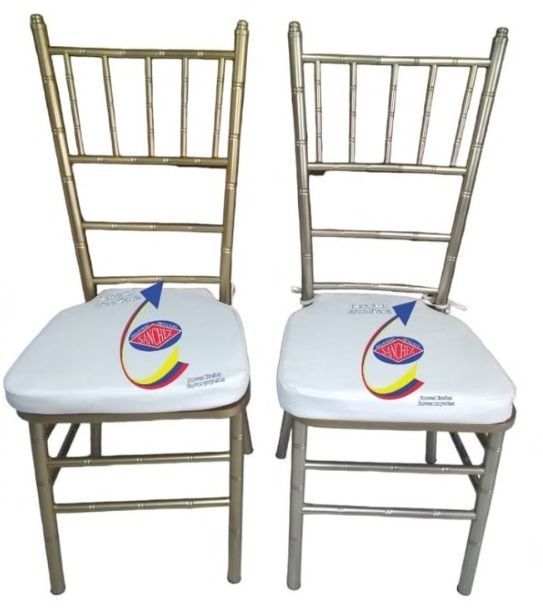 Dos sillas Chiavari doradas con cojines blancos y coloridos logotipos circulares estampados en los asientos.