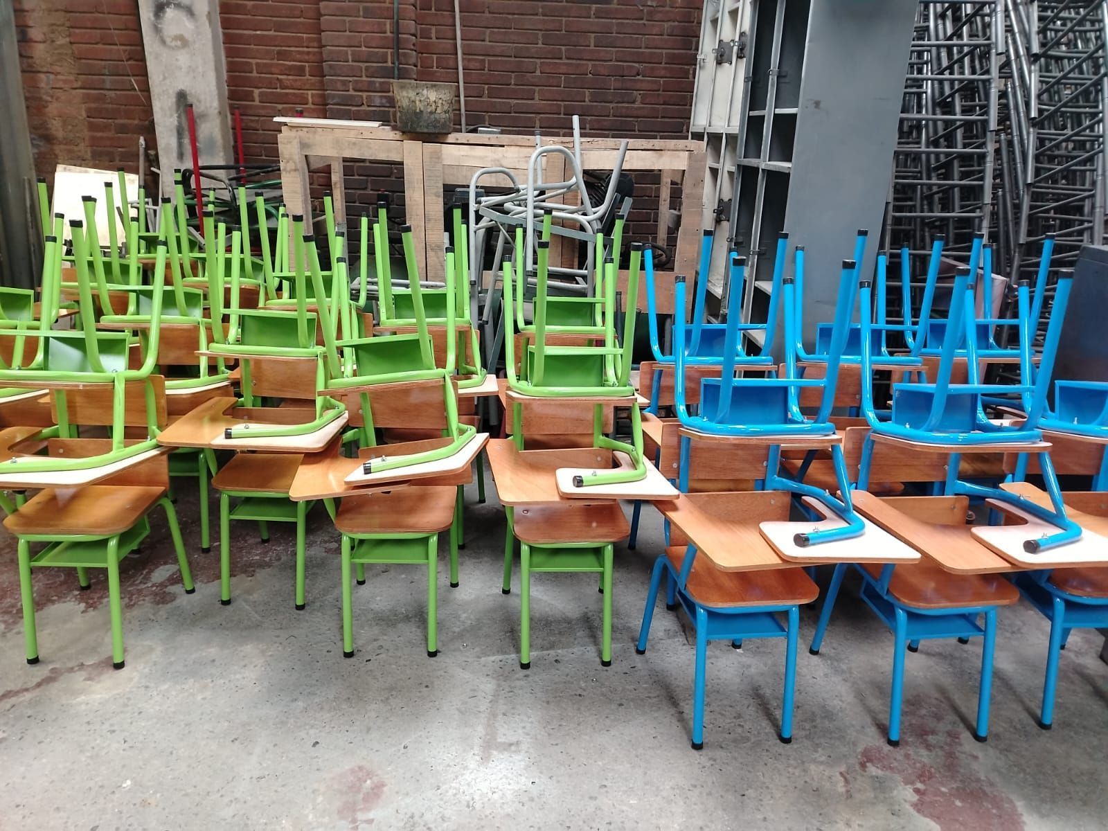 Filas de coloridos pupitres y sillas escolares apiladas en un patio