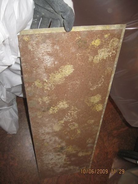 Close-up of weathered wooden boards with a yellowish stain against a brown textured background.