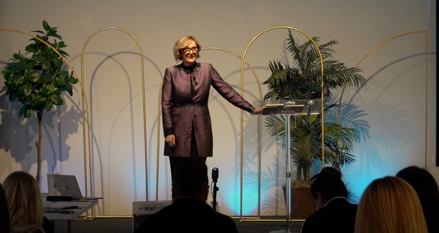A woman is standing at a podium giving a speech to a group of people.