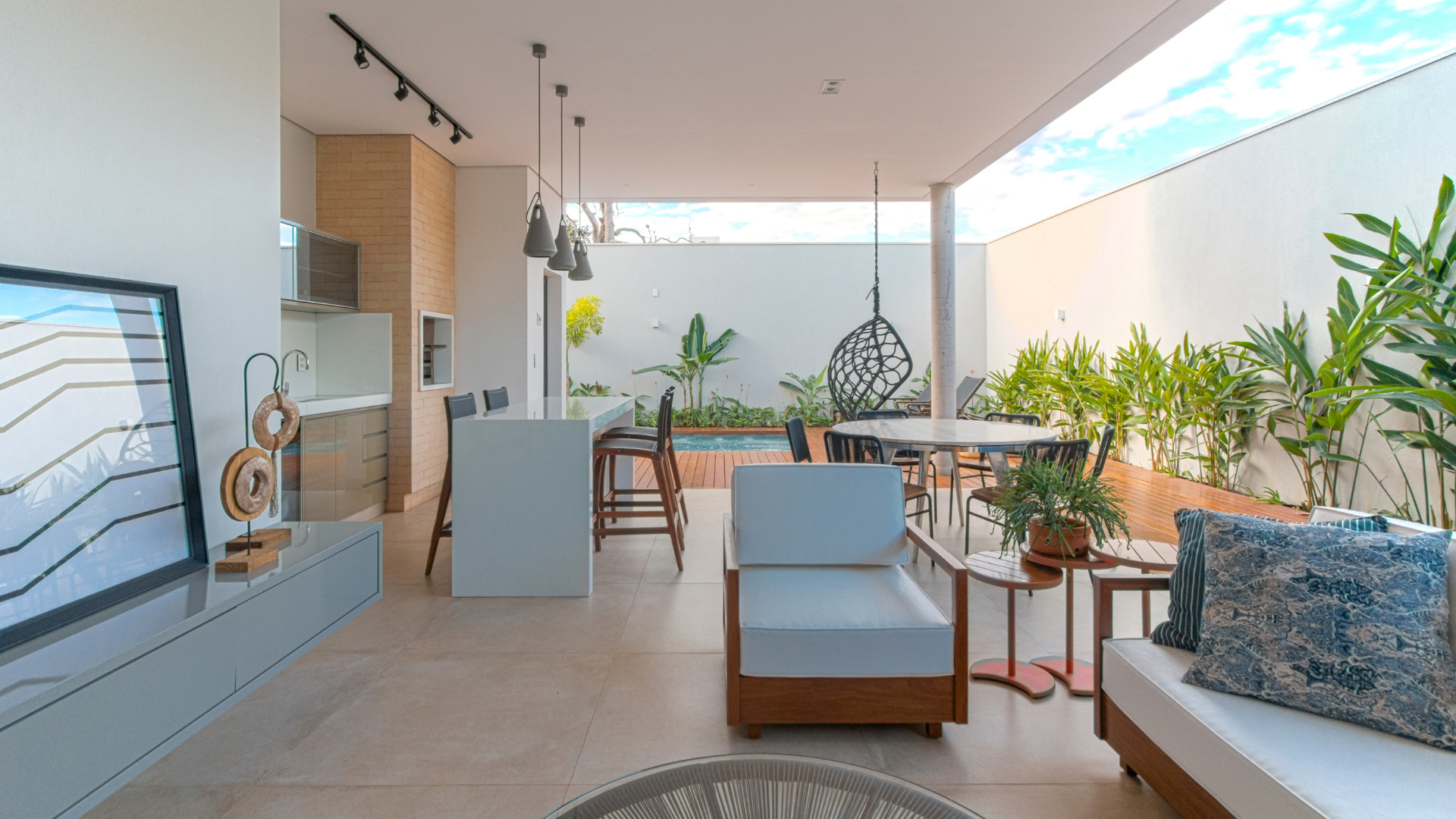Open-plan living space with kitchen, seating area, and outdoor dining near a small pool.