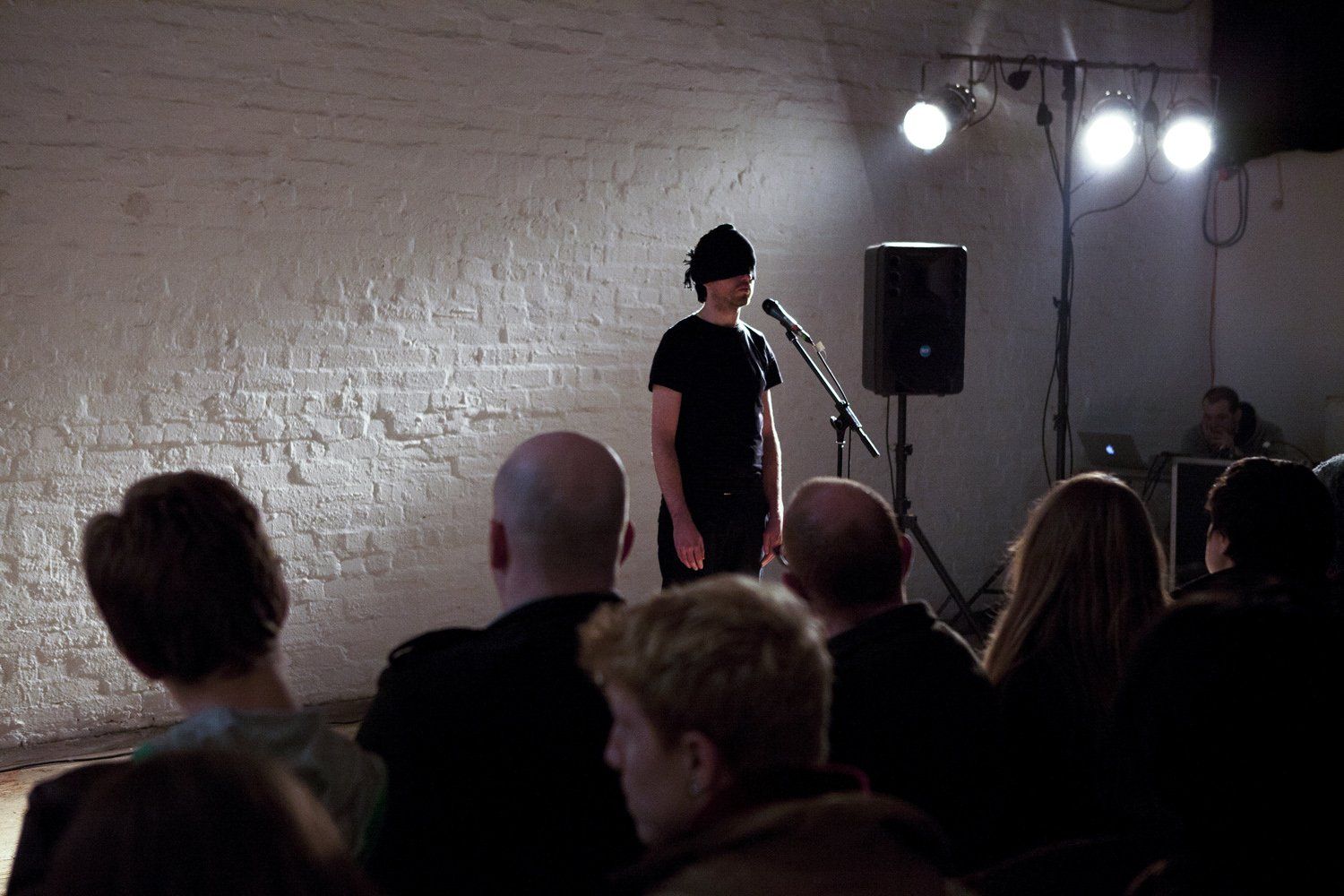 A man is standing in front of a microphone in front of a crowd of people