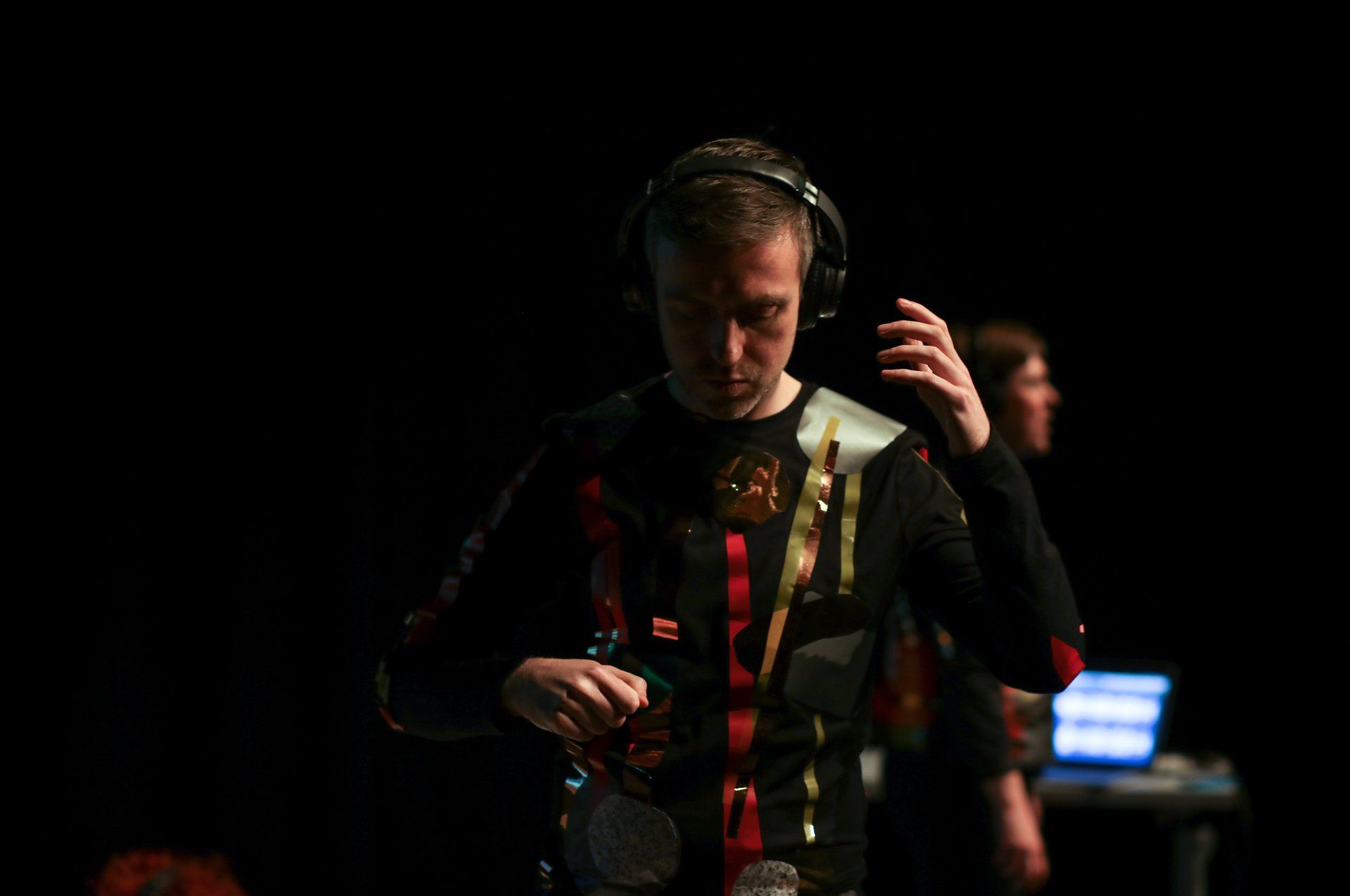 A man wearing headphones is standing in a dark room.