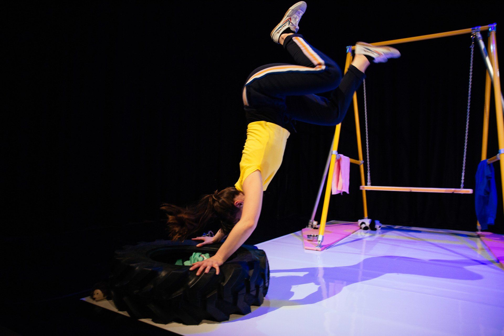 A person is doing a handstand on a tire on a stage.
