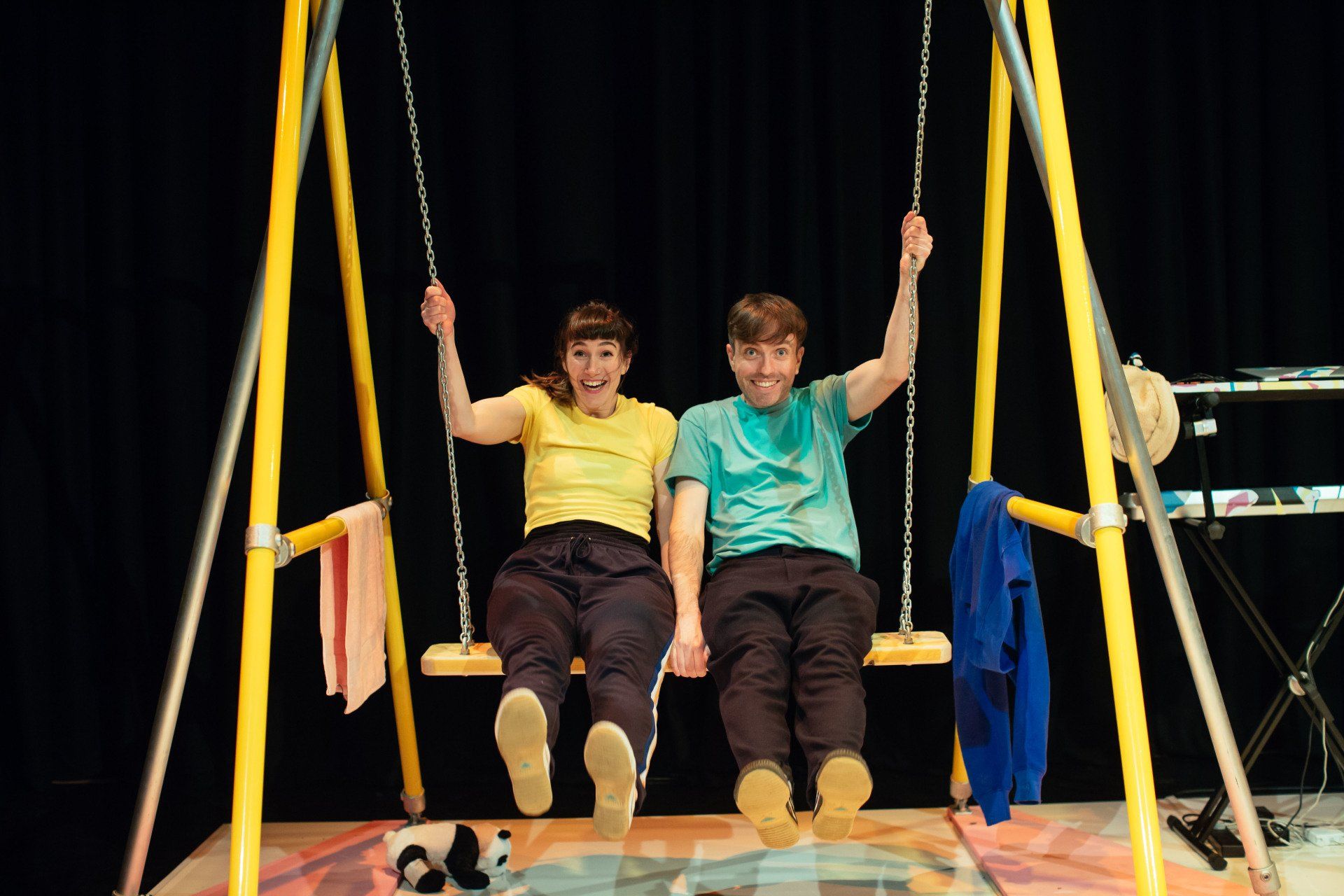 A man and a woman are sitting on a swing holding hands.