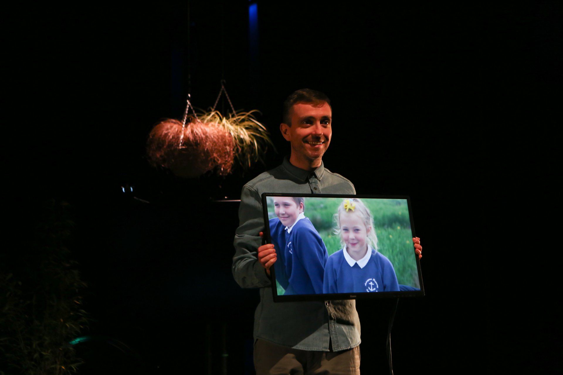 A man is holding a picture of two children on a screen.