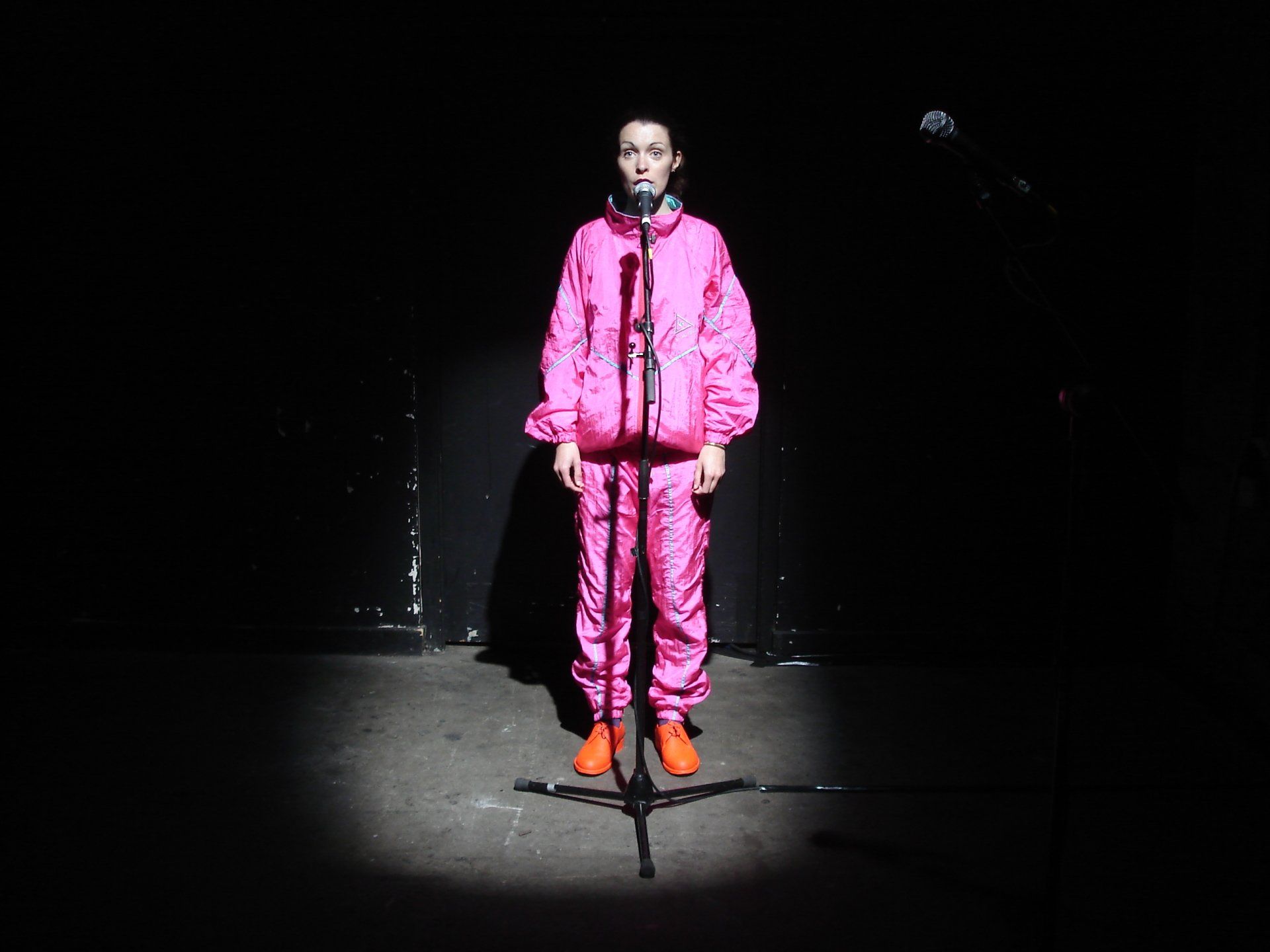 A person in a pink suit is standing in front of a microphone.