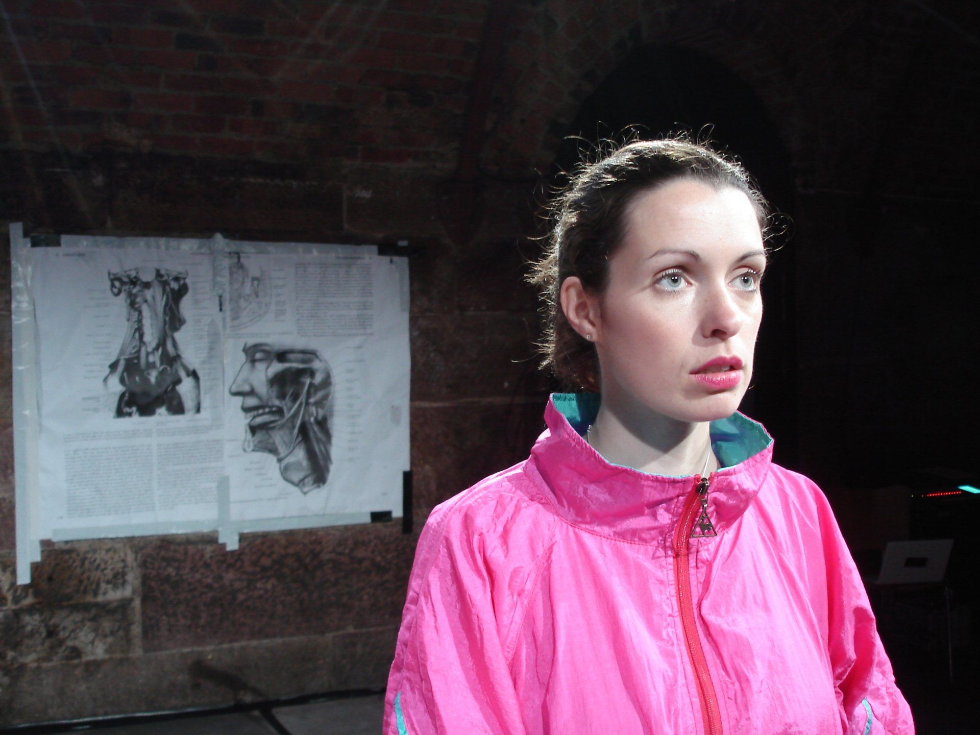 A woman in a pink jacket is standing in a dark room