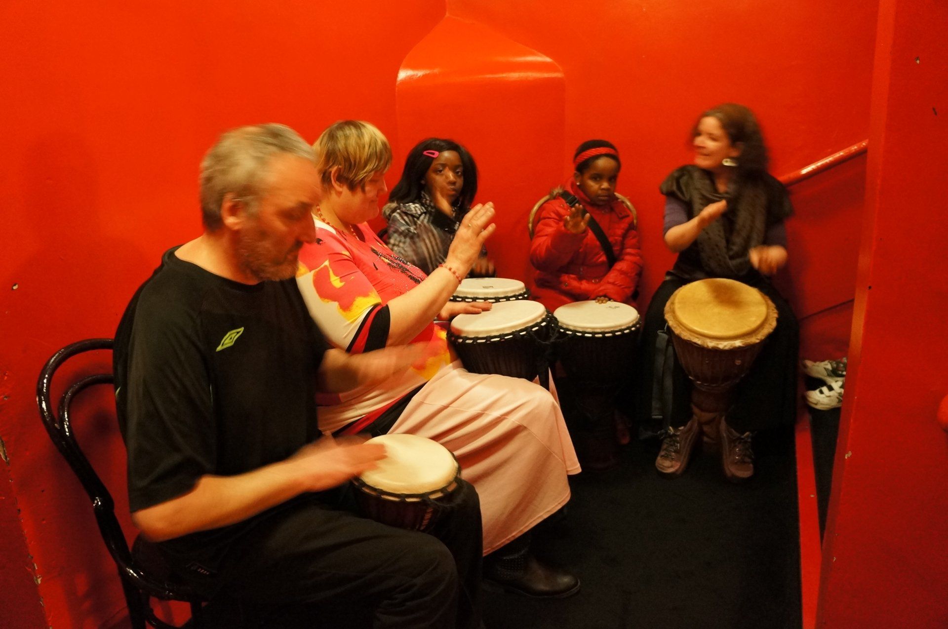 A group of people are playing drums in a red room