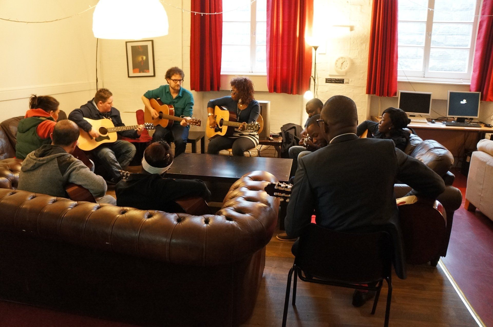 A group of people are playing guitars in a lounge area.