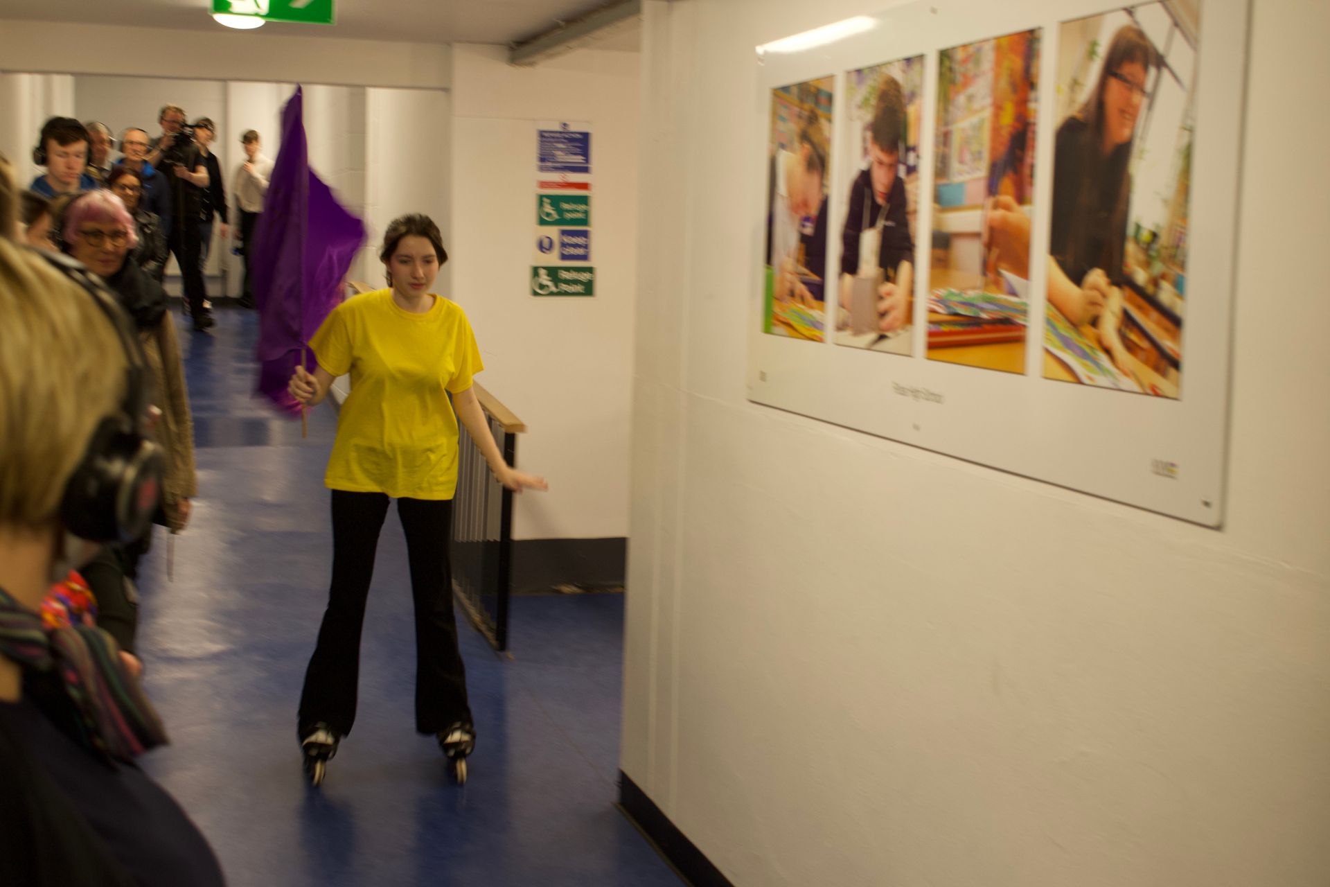 A girl in a yellow shirt is rollerblading in a hallway