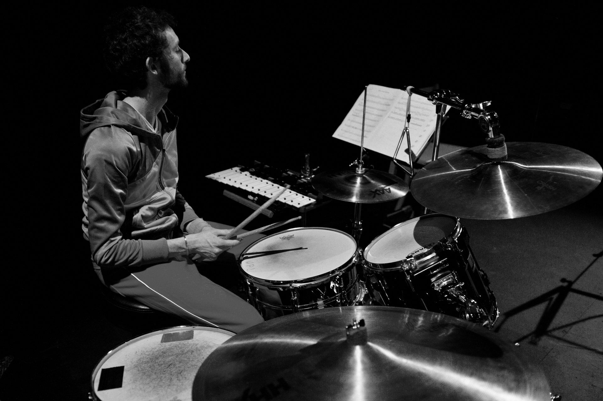 A man is playing drums in a black and white photo.